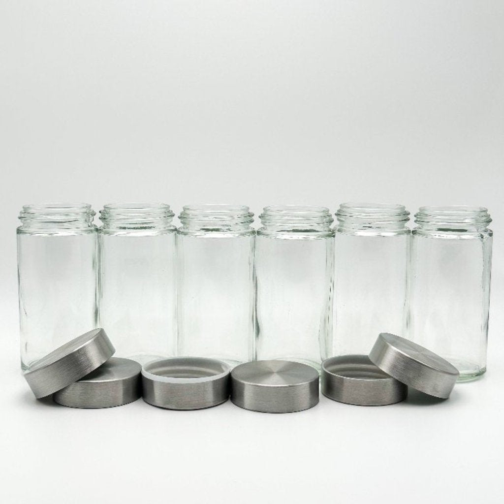 JUV Juicing Bottles aligned in a straight line with the caps sitting casually infront with a white background